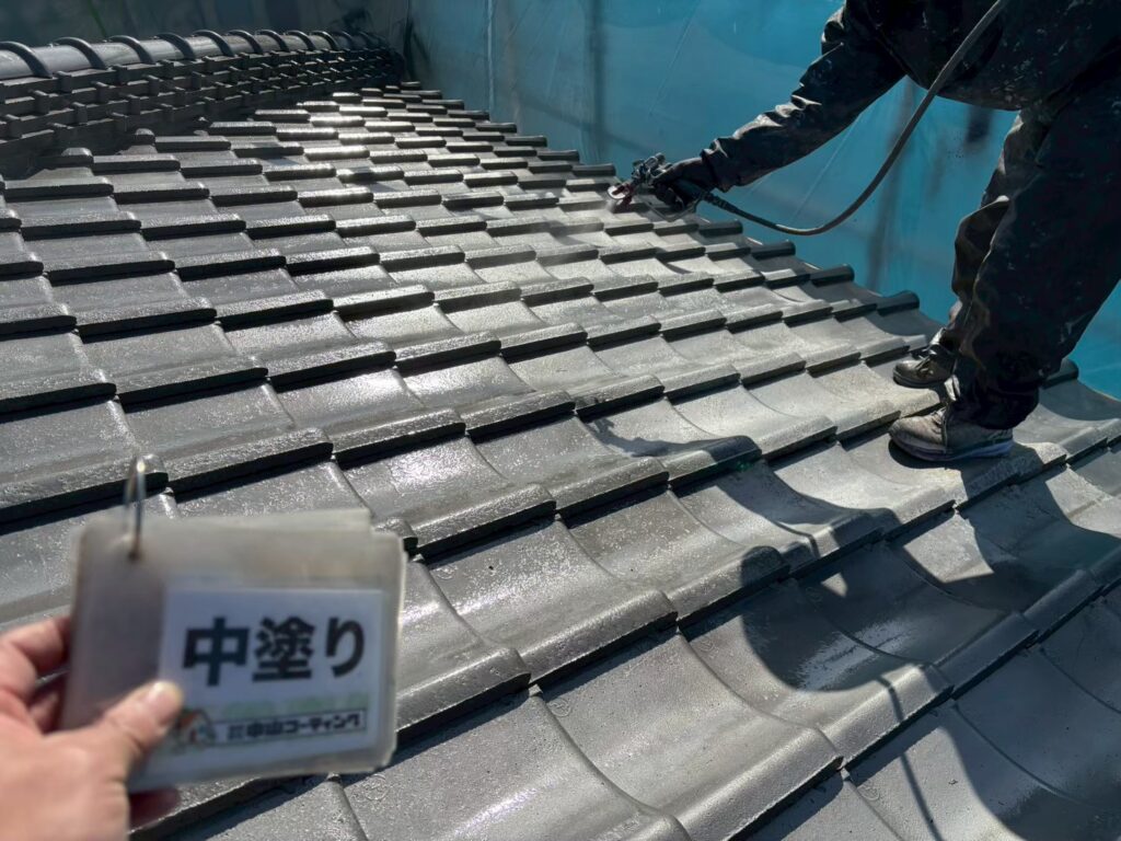 屋根瓦の中塗りを行い、瓦の形状に沿って塗料を均一に吹き付けています