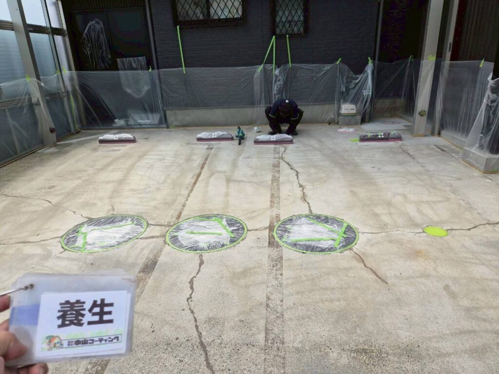 マンホールや車止めを丁寧に養生し、塗料の付着を防ぎます