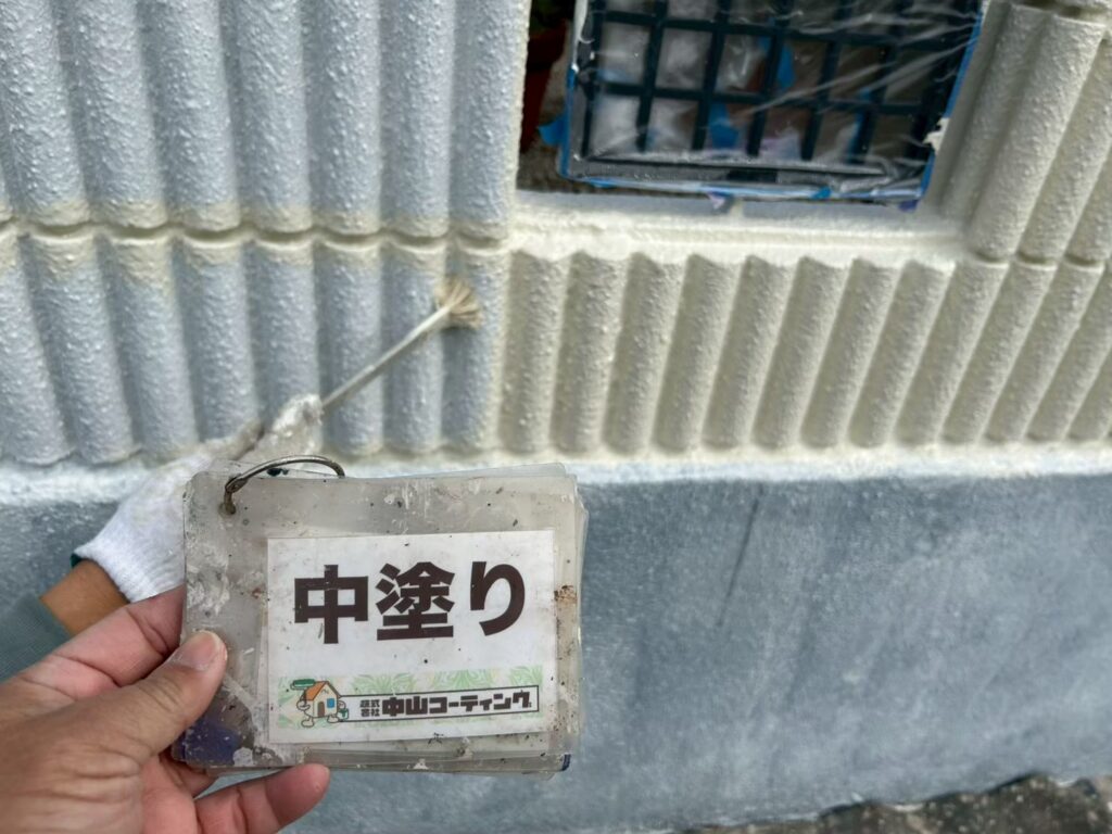 刷毛で塀の凹凸に合わせて、細かな部分まで丁寧に中塗りを進めます