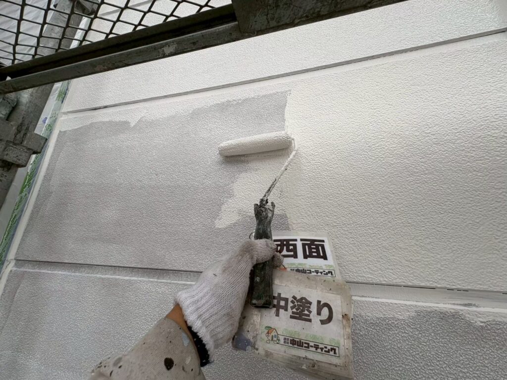 下塗りを終えた外壁に中塗りを重ねています