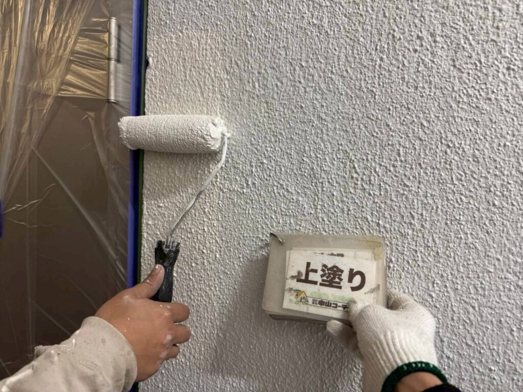 上塗り塗料をローラーで丁寧に塗り重ね、外壁全体の色合いと仕上がりを整えていきます