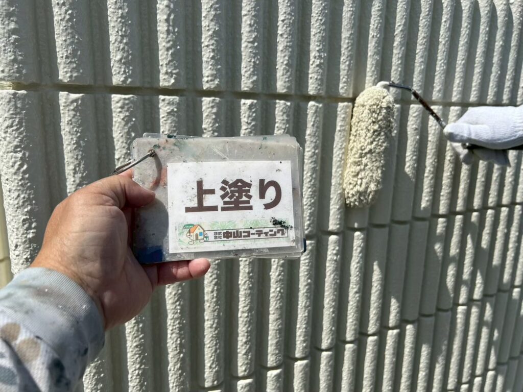 塀の凹凸にも塗料が行き渡るよう、ローラーで丁寧に上塗りを行います