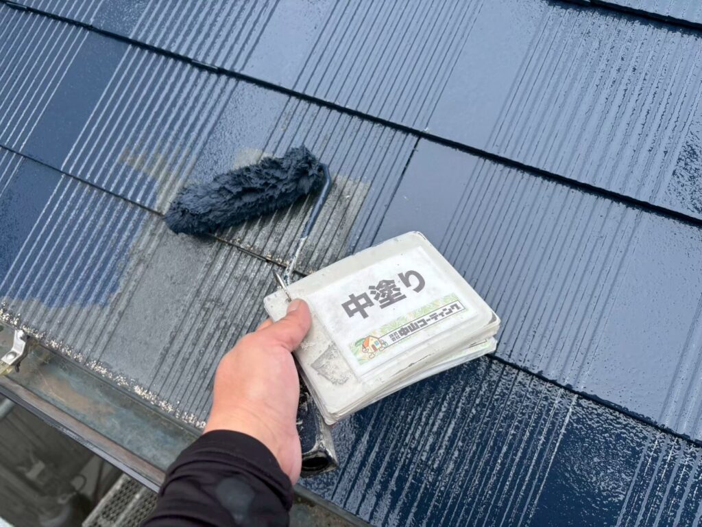 下塗り後のスレート屋根に中塗りを行っています。ローラーで仕上げ塗料を均一に塗布し、必要な塗膜厚を確保していきます