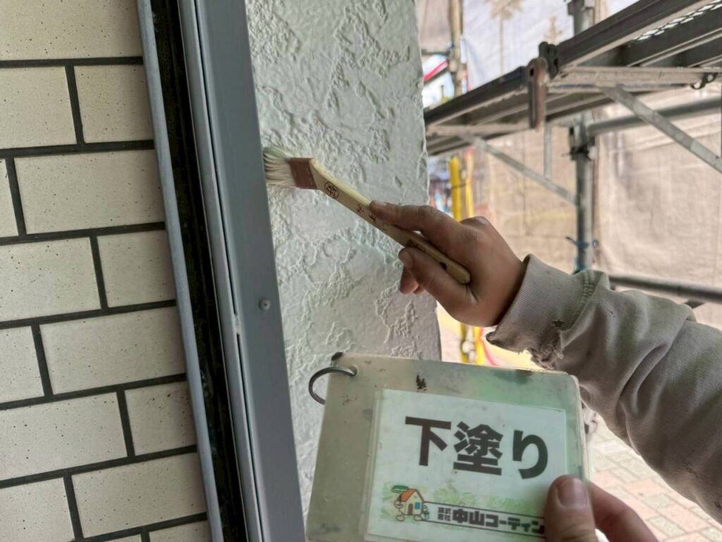 外壁の凹凸や際まで塗り残しがないよう、刷毛で丁寧に下塗り材を塗布していきます