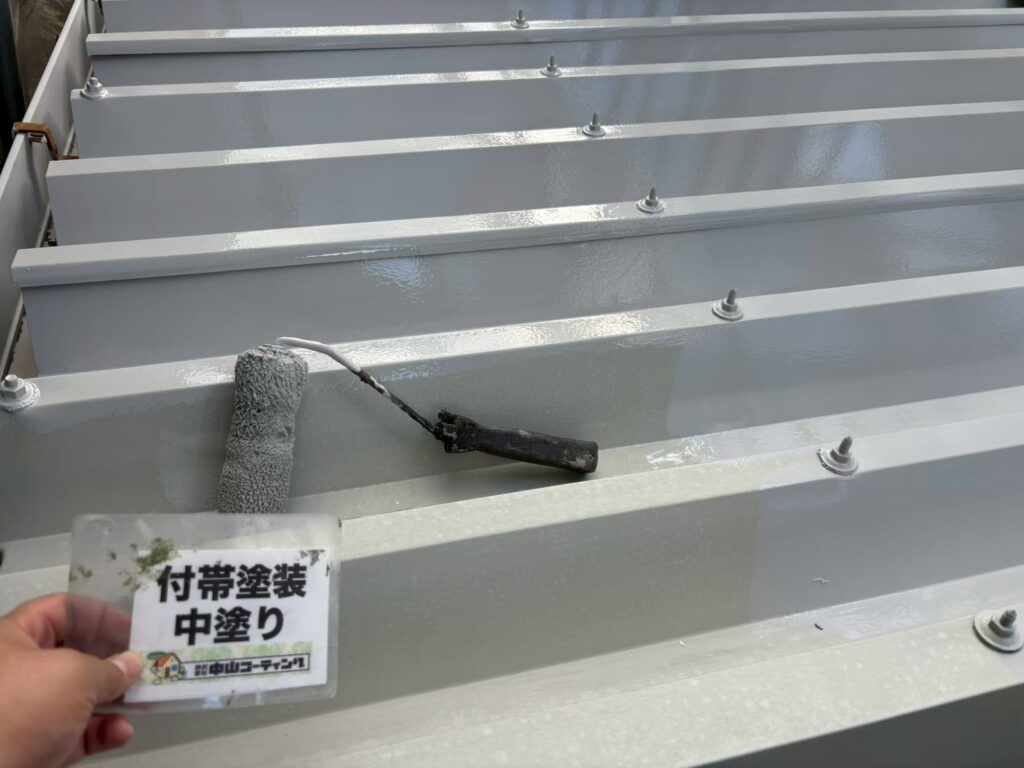 錆止めによる下塗りを終えた折板屋根に、中塗りを施工しています