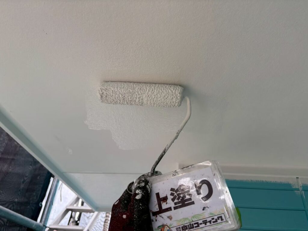 軒天の上塗りをローラーで施工しています。塗りムラや塗り残しがないよう均一に塗布し、美観を整えながら仕上げています