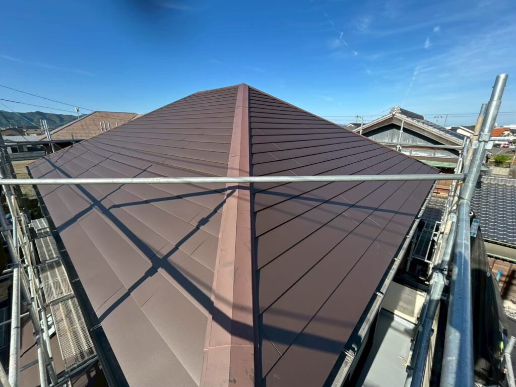 屋根カバー工法によって、新しい屋根材が全面に施工された状態です。落ち着いたブラウン系の色合いで統一され、屋根全体がすっきりとした印象になりました