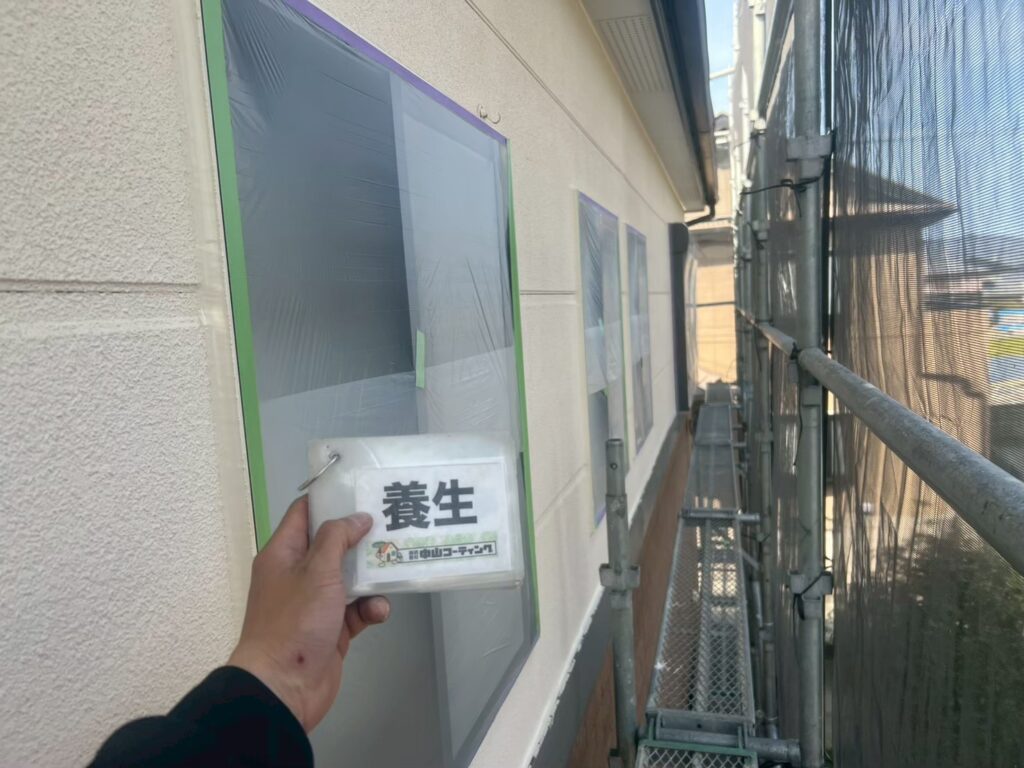 外壁に面した窓を一つひとつ養生し、塗装範囲との境目を丁寧に整えています