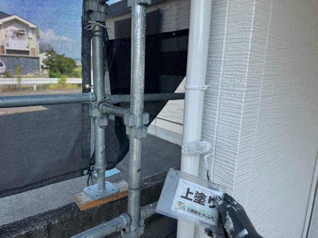縦樋に、ローラーで丁寧に上塗りを行っています