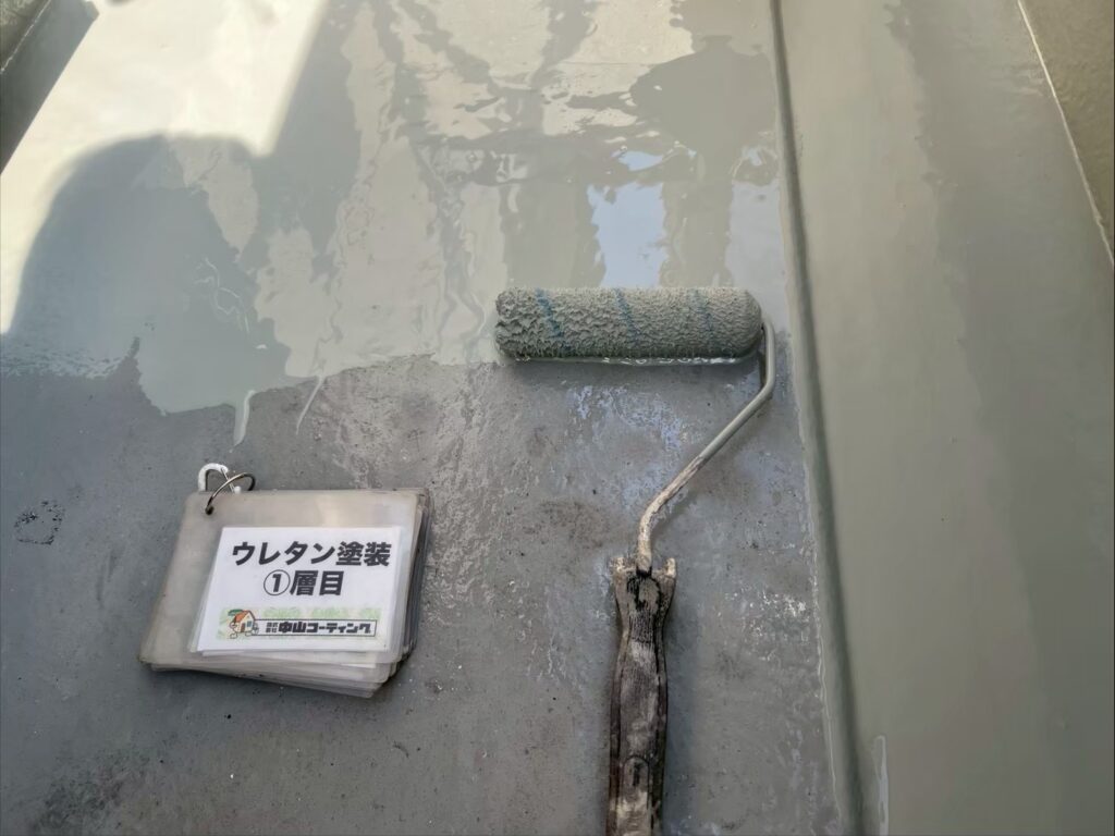 ベランダ床面にウレタン防水材の1層目を施工しています。塗りムラや塗り残しが生じないよう、ローラーで丁寧に塗り重ねながら、防水層の土台を形成していきます