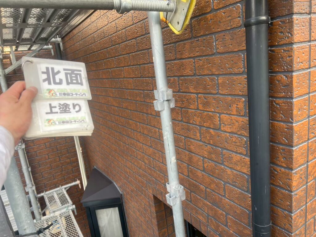 WB多彩仕上げ工法による上塗り工程です。塗装面には自然な艶が生まれ、ブラウン系の多彩な色合いとレンガ調の凹凸が美しく調和しています