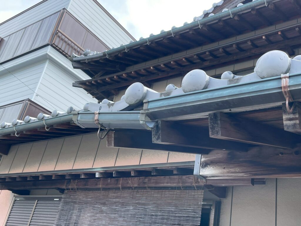 玄関屋根の木部には色あせが見られ、雨樋の継ぎ目にもズレが確認できます