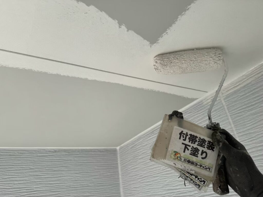 軒天に、ローラーで下塗りを行っています