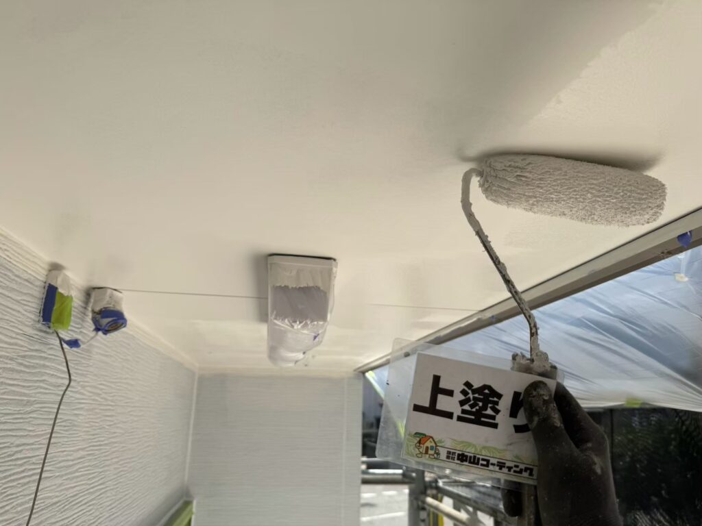 軒天に上塗りを重ね、均一に塗り広げています