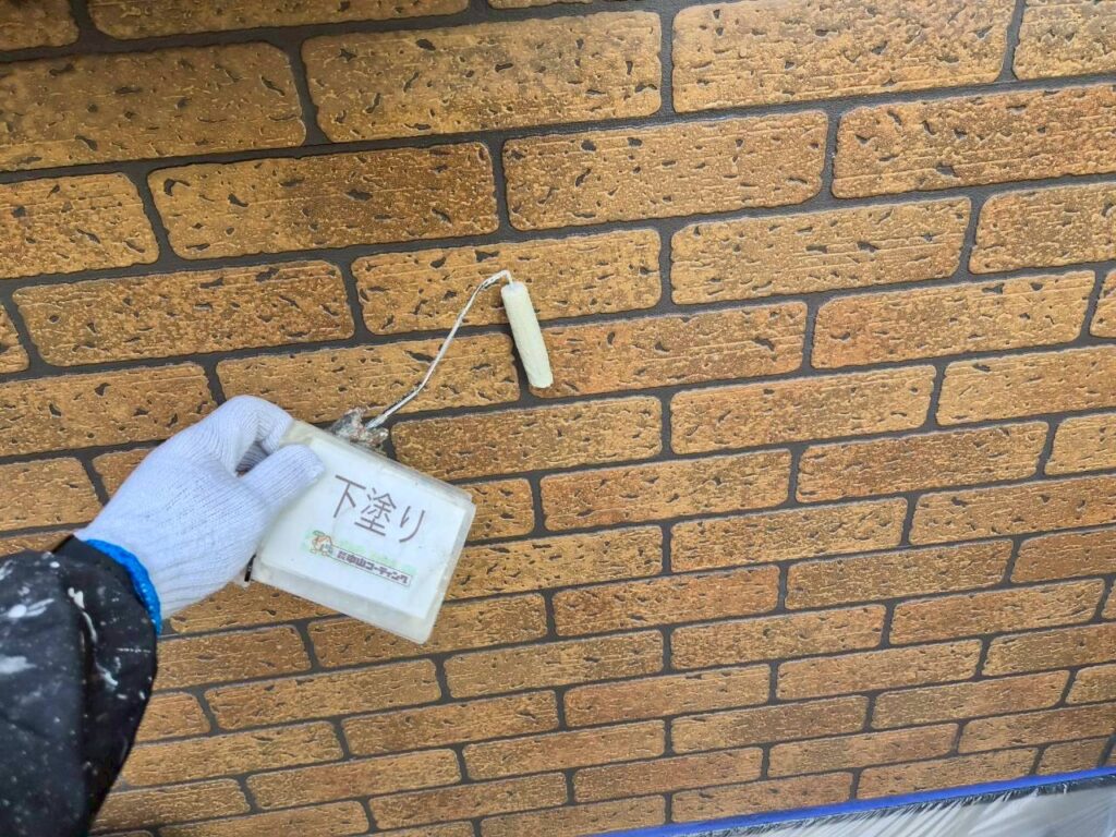 試し塗りを行う外壁部分に、ローラーで下塗り材を塗布しています