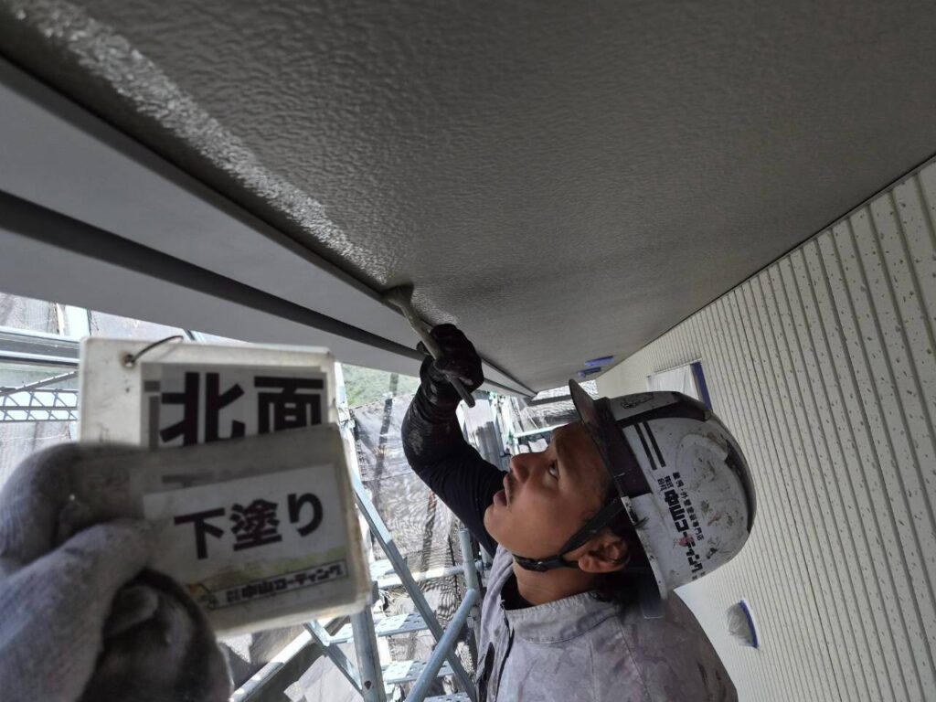 軒天の端を、刷毛で下塗りしています